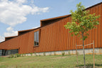 Modern building with 1.5 inch nail strip standing seam metal wall panels installed as vertical wall cladding in a rust finish