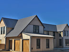 Modern house with dark gray standing seam metal roof panels installed on a steep roof